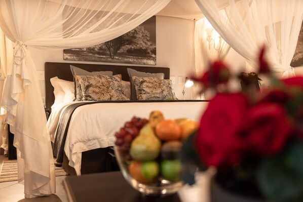 A hotel room with a bed, a fruit bowl, and a wall-mounted picture. - Kruger Eden Lodge (Nkomazi)
