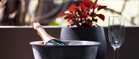 A bottle of champagne in a bowl, a glass, and a potted plant with red leaves.