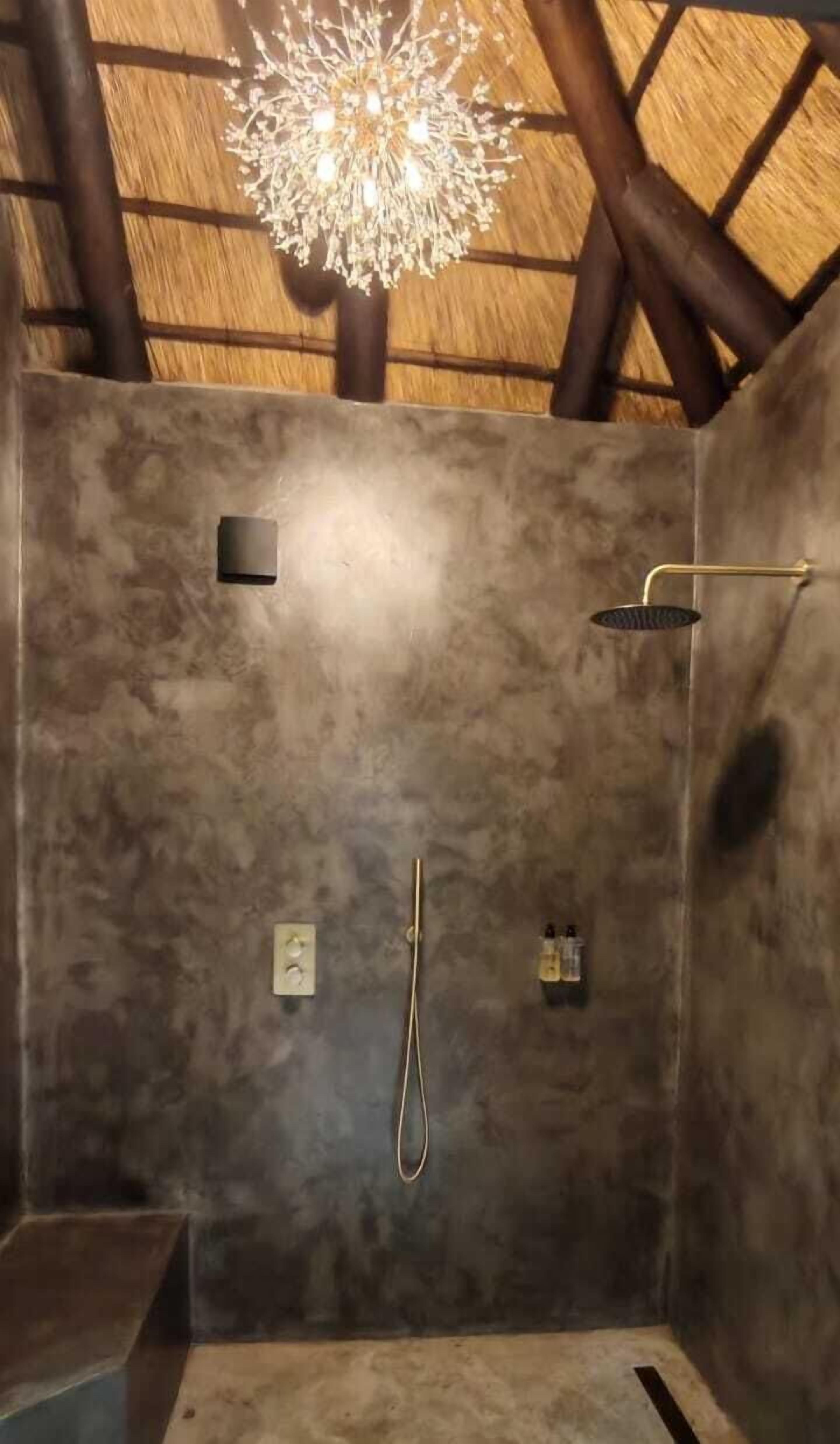 A shower area with a textured wall, a handheld showerhead, and a wall-mounted faucet.