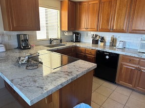 Enjoy cooking and preparing meals in this well-equipped kitchen with a sleek island, wooden cabinets, and appliances.