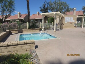 Relax by the pool surrounded by lush greenery and a charming pergola.
