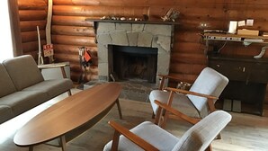 L’intérieur d’un chalet confortable, avec une cheminée en pierre, des meubles en bois et un mur en bois.