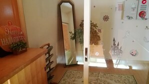 Een hotel receptie met een houten balie, een spiegel, een potplant en een kamerbreed tapijt.