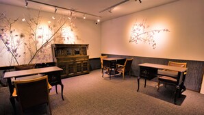 A room with a long table, several chairs, a cabinet, and wall-mounted decorations.