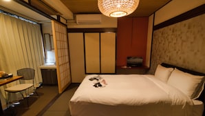A hotel room with a bed, a desk, a chair, and a television.