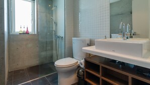 A modern bathroom with a glass shower enclosure, a white toilet, and a built-in sink with a mirror. - Yuki Ten by H2 Life (Kutchan)