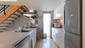 A modern kitchen with a wooden staircase, stainless steel appliances, and a large refrigerator. - Yuki Ten by H2 Life (Kutchan)