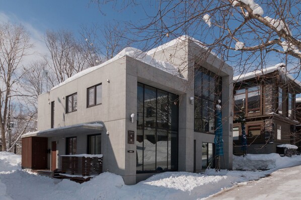 Un edificio moderno de dos pisos con ventanas amplias y un porche cubierto.