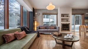 Un salon moderne avec un canapé vert, un divan gris et une table basse en bois.