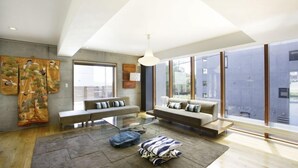 A modern living room with a sofa, a glass coffee table, and a large window offering a view of the city. - Asanagi 3 bedroom by Hokkaido Tracks (Kutchan)