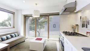 Cozinha moderna com fogão a gás, facas penduradas e vista para área externa por meio de grandes portas de correr.