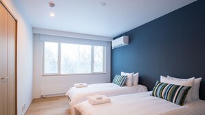 Ein Hotelzimmer mit zwei Betten, einem großen Fenster und einer Klimaanlage.