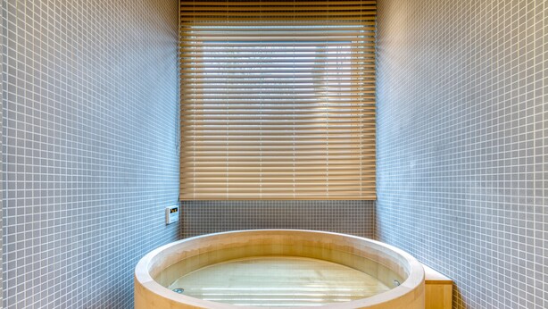 A wooden bathtub in a tiled room with a window and blinds. - Chalet W by H2 Life (Kutchan)