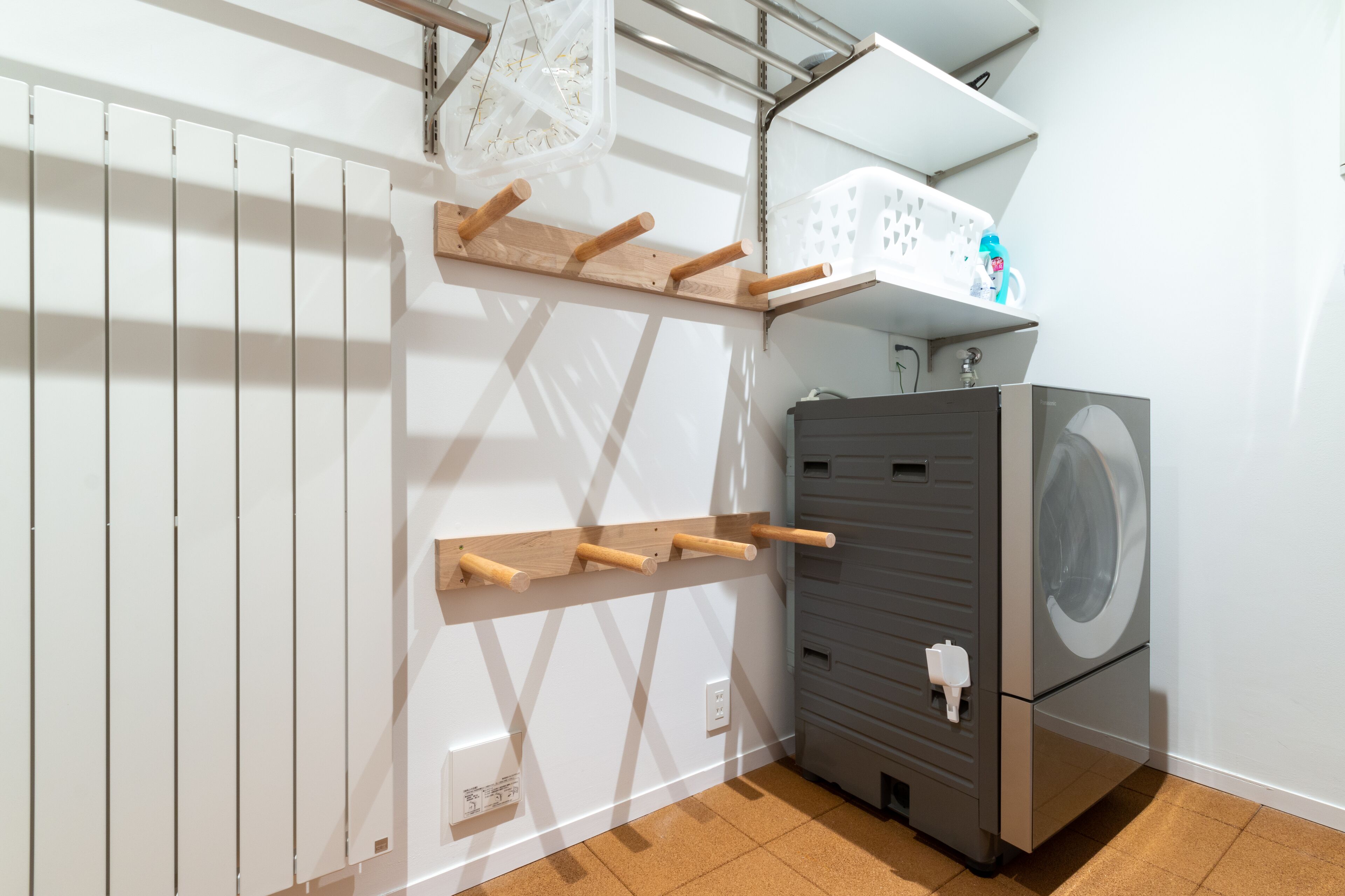 A laundry room with a washing machine, a drying rack, and a shelf with laundry baskets.