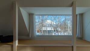 A room with a large window offering a view of a snowy mountain and trees. - Chalet W by H2 Life (Kutchan)