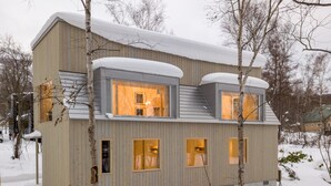 A modern, multi-story building with large windows and a sloped roof covered in snow. - Chalet W by H2 Life (Kutchan)
