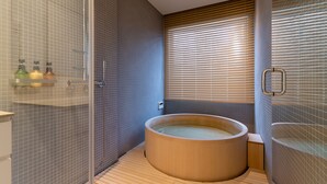 A modern bathroom with a wooden bathtub, tiled walls, and a glass shower enclosure. - Chalet W by H2 Life (Kutchan)