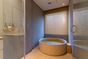 Bañera con ducha, pantuflas, toallas