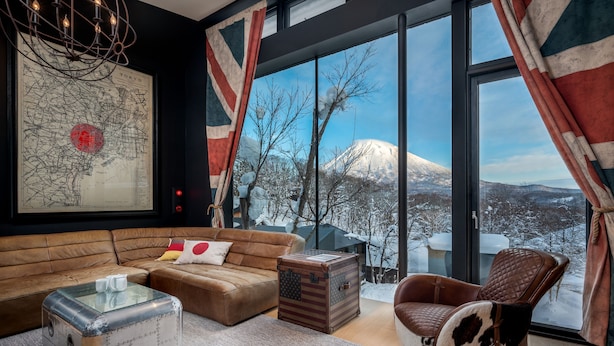 Una sala de estar acogedora con un ventanal grande, un mapa en la pared y vistas a una montaña nevada.