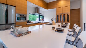 A modern kitchen with wooden cabinetry, stainless steel appliances, and a large island with seating.