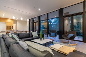 A modern living room with a sectional sofa, a coffee table, and two rocking chairs.