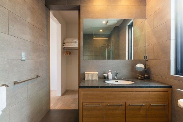 A modern bathroom with a large mirror, a sink, and a shower area.