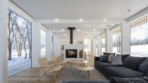 A spacious living room with a fireplace, large windows, and a view of a snowy outdoor area.