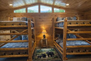 A cabin with two bunk beds, a small table with a lamp, and a rug with animal prints. - All the amenities you need for R&R and/or fun, can sleep 18, Game Room. (gatlinburg)