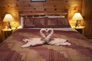 A wooden cabin-style room with a bed, two nightstands with lamps, and a heart-shaped towel arrangement on the bed. - All the amenities you need for R&R and/or fun, can sleep 18, Game Room. (gatlinburg)