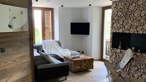 Una sala de estar moderna con un sofá, una mesa de centro y un televisor montado en la pared.