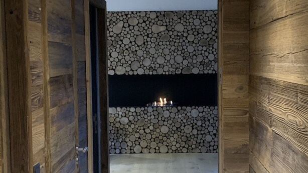 Un interior de madera con pared de piedra y chimenea.