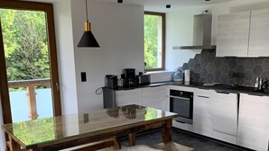 Una cocina moderna con una mesa de vidrio, bancos de madera y vistas al exterior.