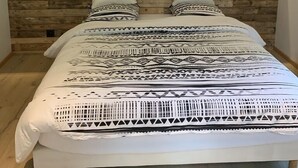 Una cama con cabecera de madera, dos lámparas de pared y ropa de cama estampada.