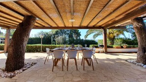 An outdoor patio with hexagonal tiles, a wooden pergola, and a table set for dining. - VILLA PLEMMYRIA. Semi-detached villa immersed in the greenery of the Plemmirio Marine Protected Oasis (Plemmirio)