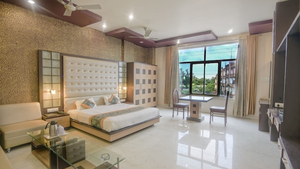 Habitación de hotel moderna con una cama grande, una mesa de centro de vidrio, un escritorio y vistas al exterior.