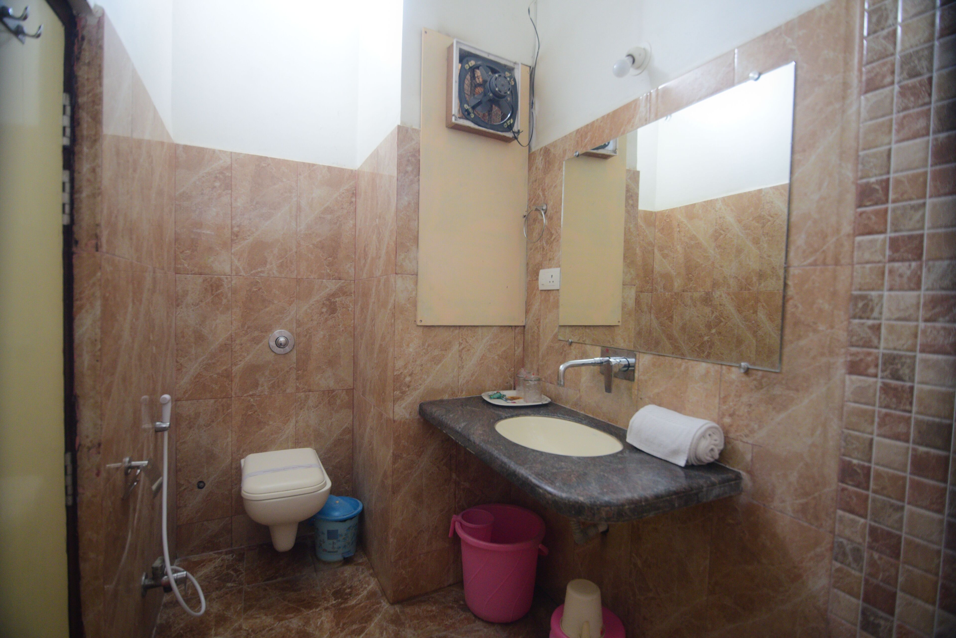 Une salle de bain avec un sol en marbre, un lavabo, des toilettes, un miroir et une douche.