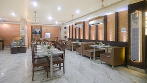 Un restaurante con una larga mesa de comedor, cabinas y una pantalla de televisión.