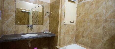 Ein Badezimmer mit Waschbecken, Spiegel, Dusche und einem Wandventilator.