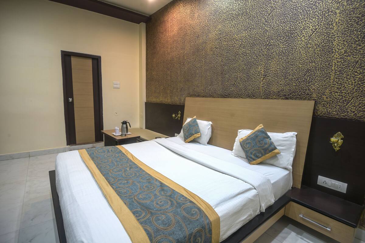 Una habitación de hotel con una cama grande, una mesita de noche y una pared con un diseño texturizado.