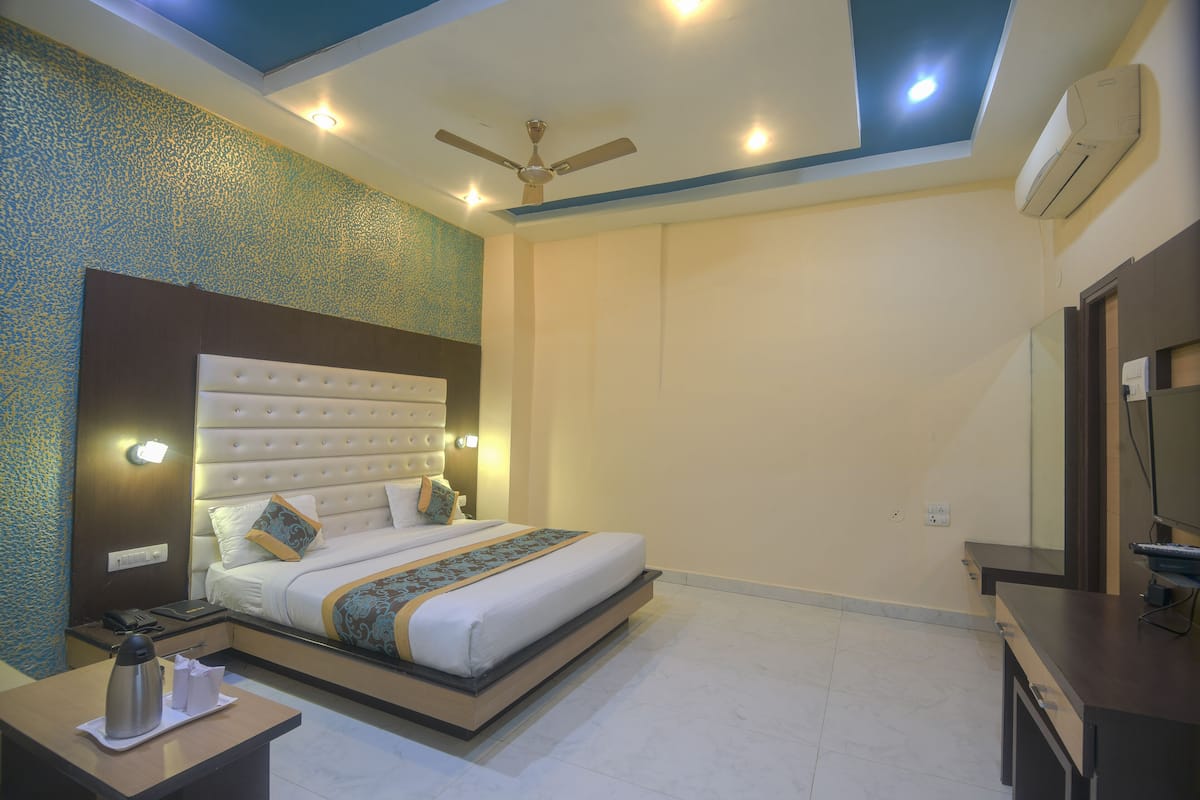Habitación de hotel moderna con una cama grande, ventilador de techo, iluminación empotrada y televisor de pantalla plana.