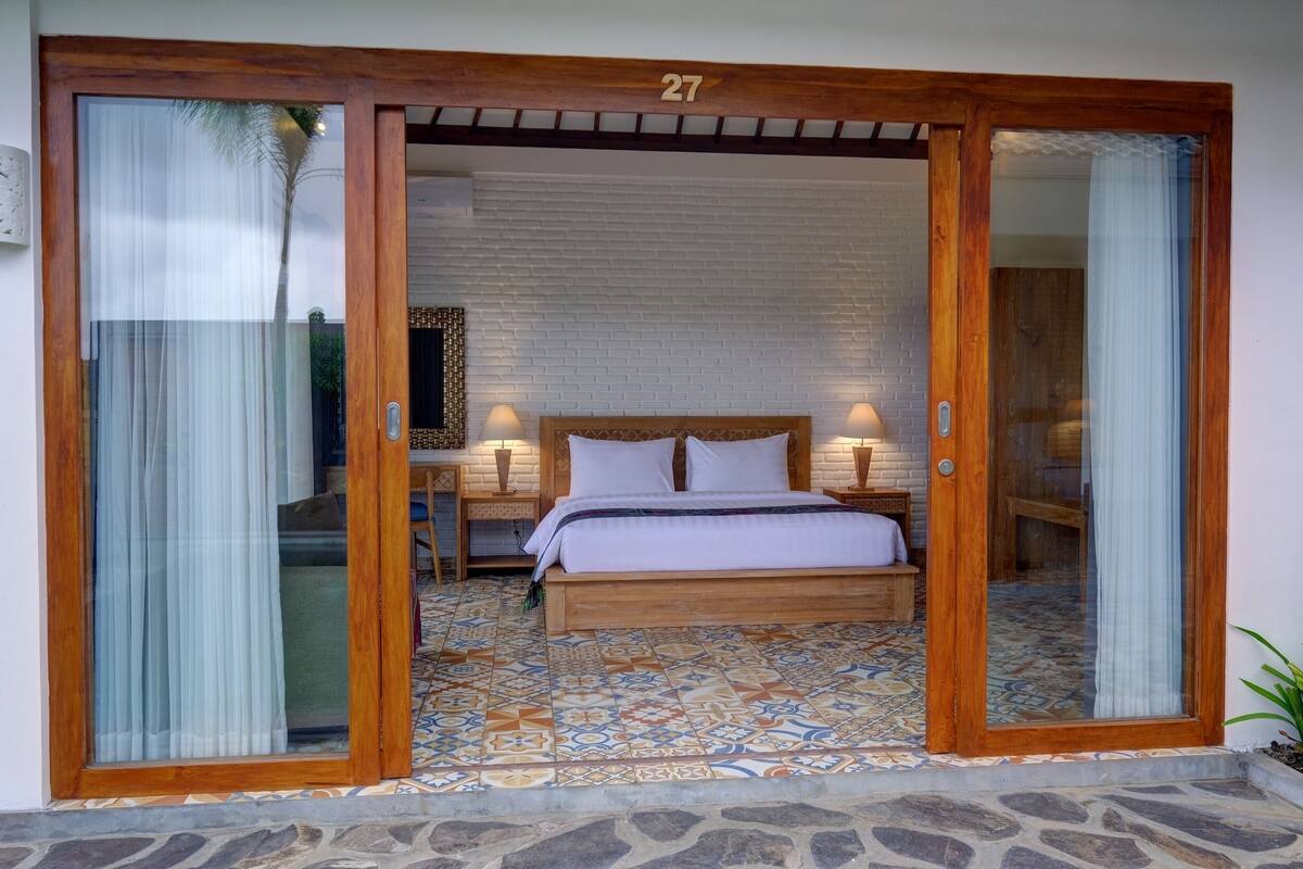 A bedroom with a large bed, wooden headboard, and a patterned floor.