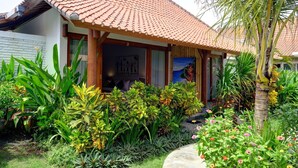 A traditional house with a tiled roof, surrounded by lush tropical plants and a palm tree. - Wide Sands Beach Retreat (Mendoyo)