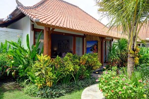 Un edificio tradicional con techo de tejas, rodeado de exuberante vegetación tropical y una palmera.