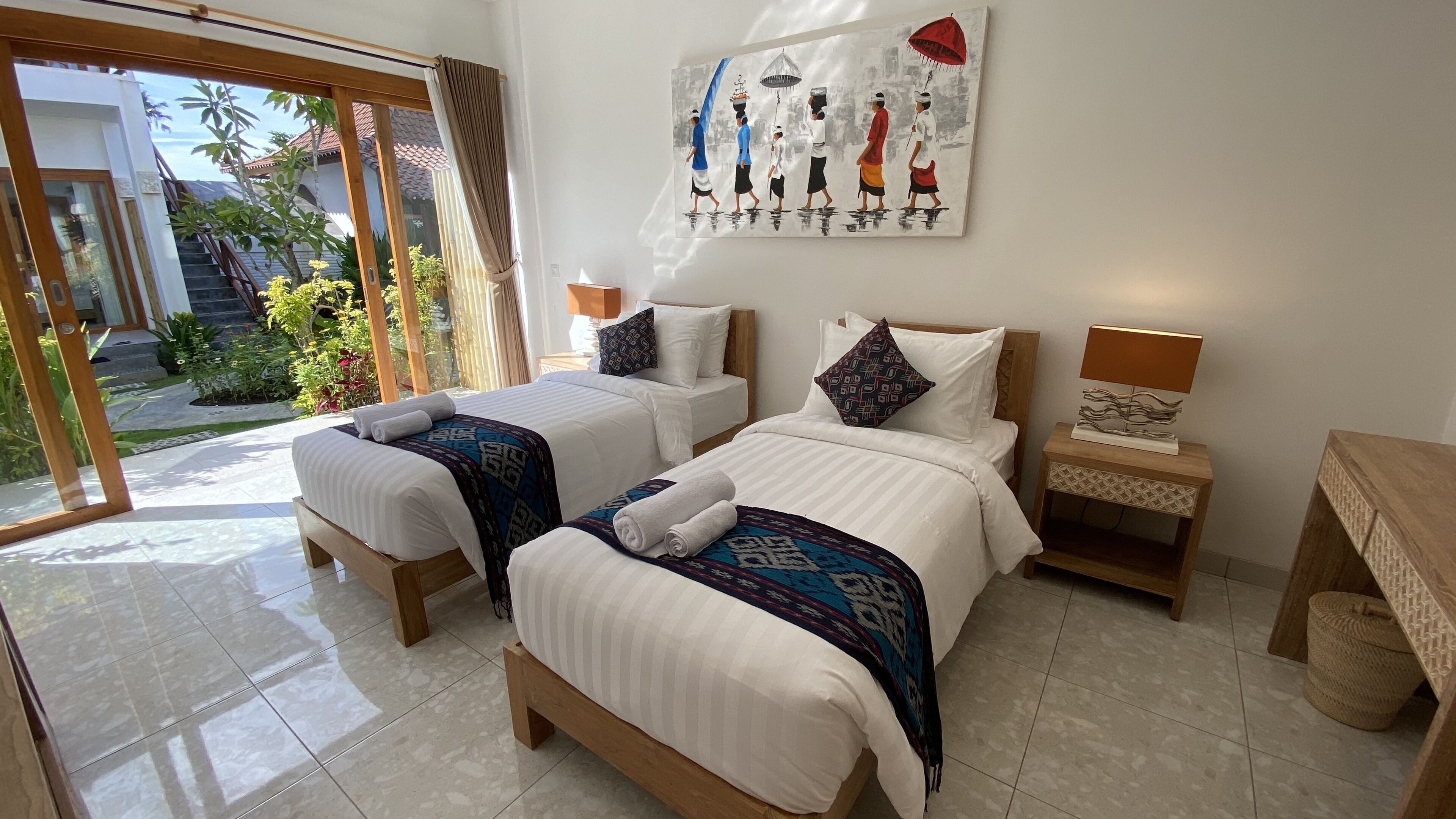 Habitación de hotel con dos camas, un cuadro en la pared, una mesita de noche y vistas al exterior.