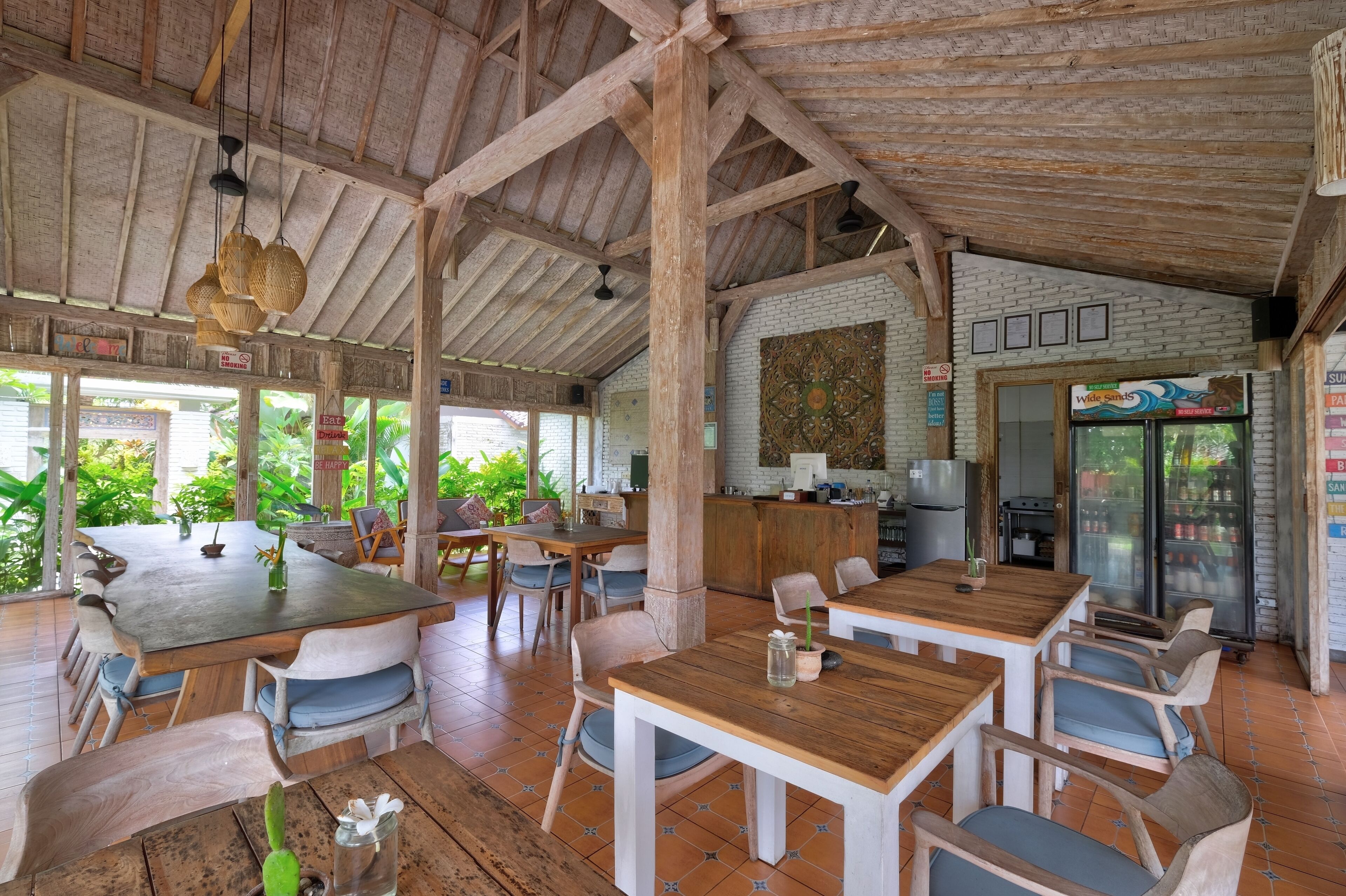 A rustic wooden interior with high ceilings and large windows. Tables and chairs are arranged for dining.