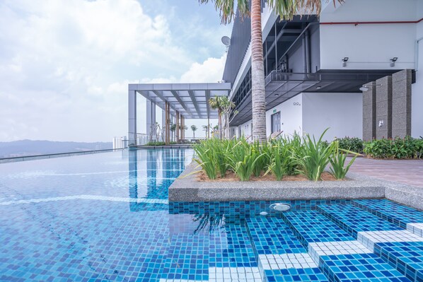 A modern hotel with a swimming pool, outdoor seating area, and a view of the city skyline.