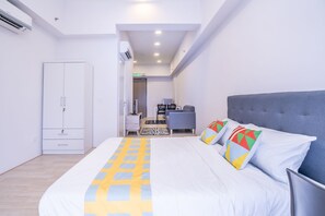 A modern hotel room with a large bed, a wardrobe, a desk, and a chair.