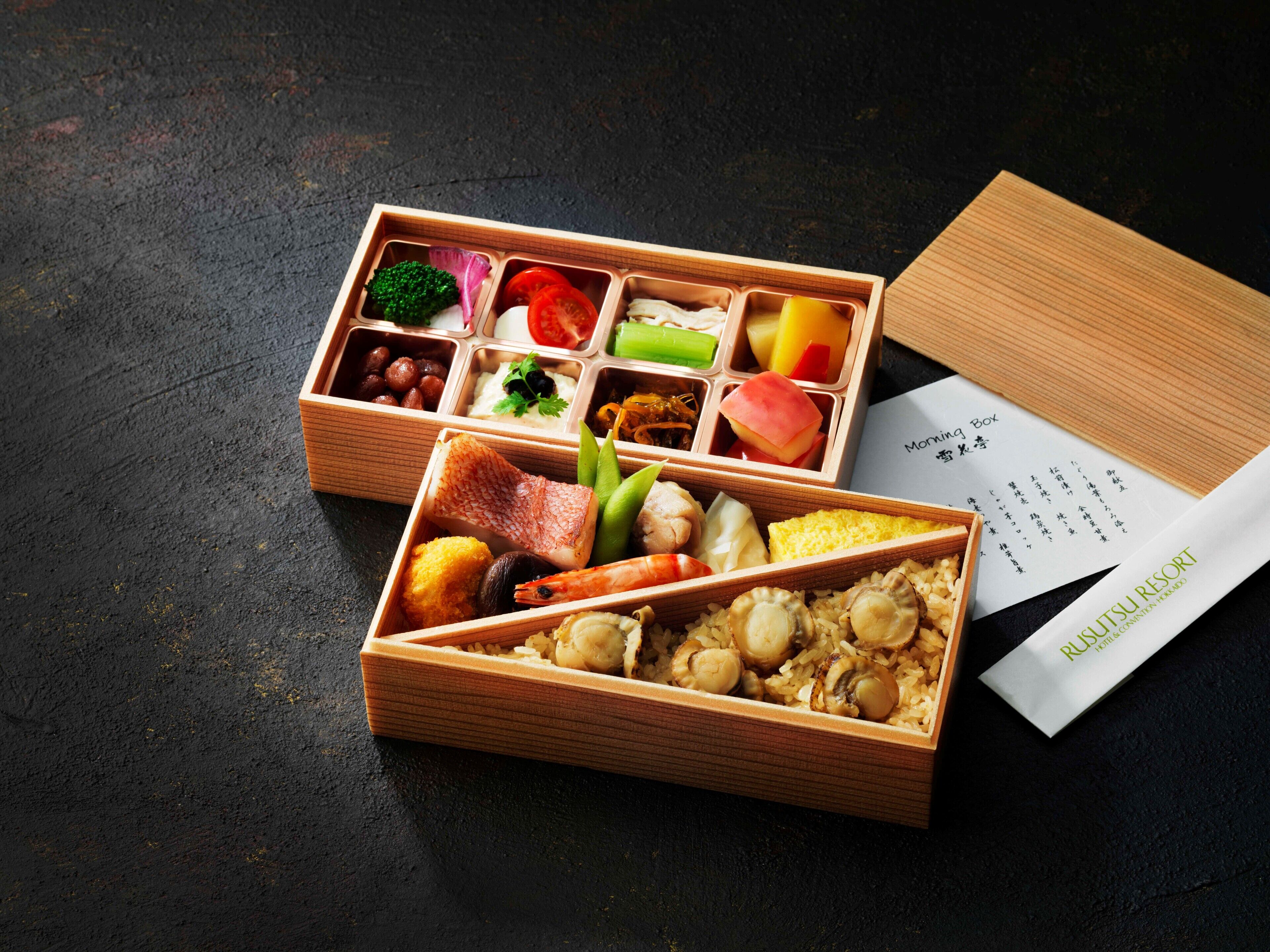 Una caja de bento de madera con diferentes alimentos y un menú.