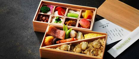 A wooden bento box with various food items and a menu.