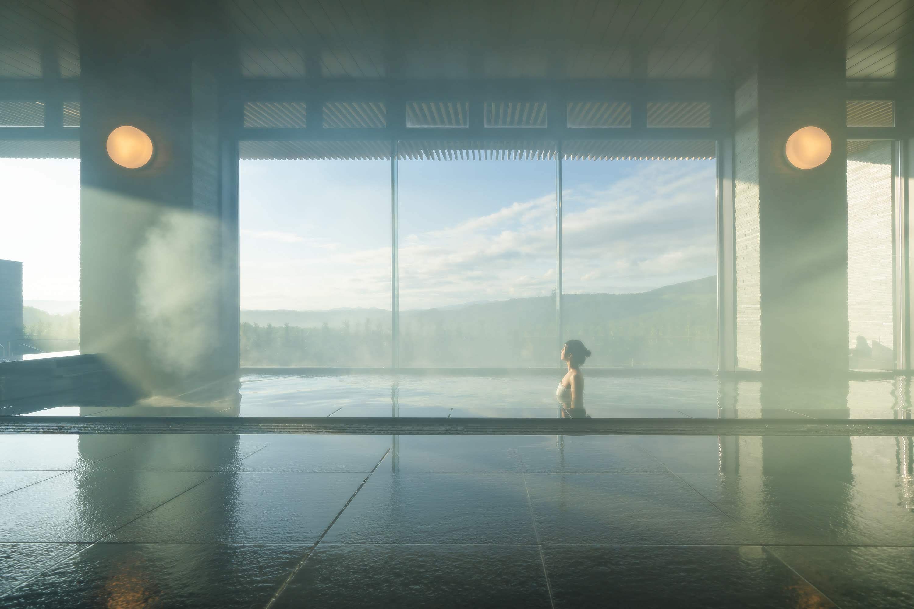 Un vaste espace intérieur doté d’une grande fenêtre donnant sur une étendue d’eau et sur des montagnes lointaines.